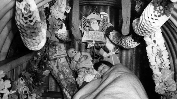 Un bambino dorme in un rifugio antiaereo addobbato con decorazioni nel Natale del 1940