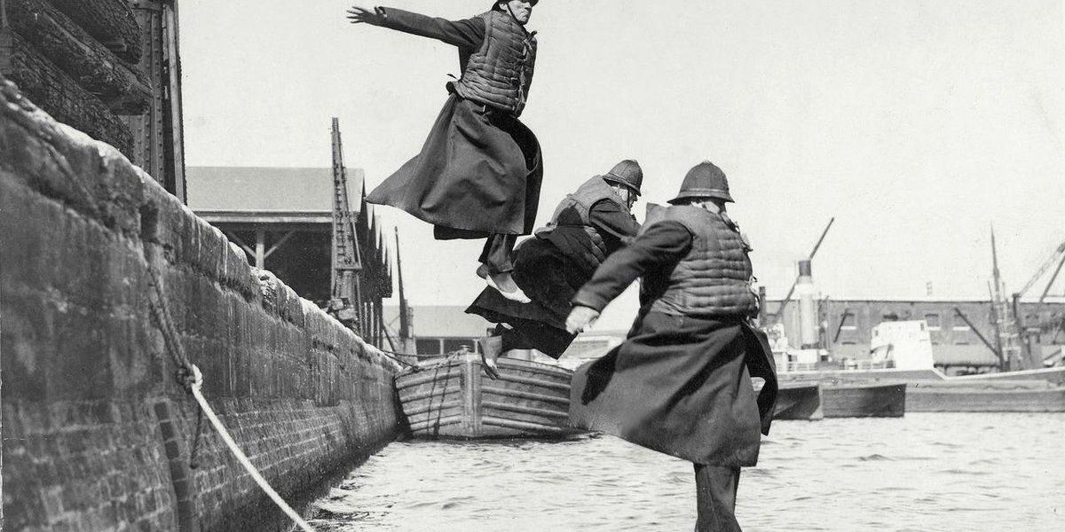 Poliziotti testano i giubbotti di salvataggio saltando in acqua a West India Docks. 1930
